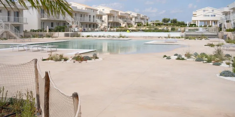 A shallow outdoor pool sits among modern residential buildings and landscaped paths.