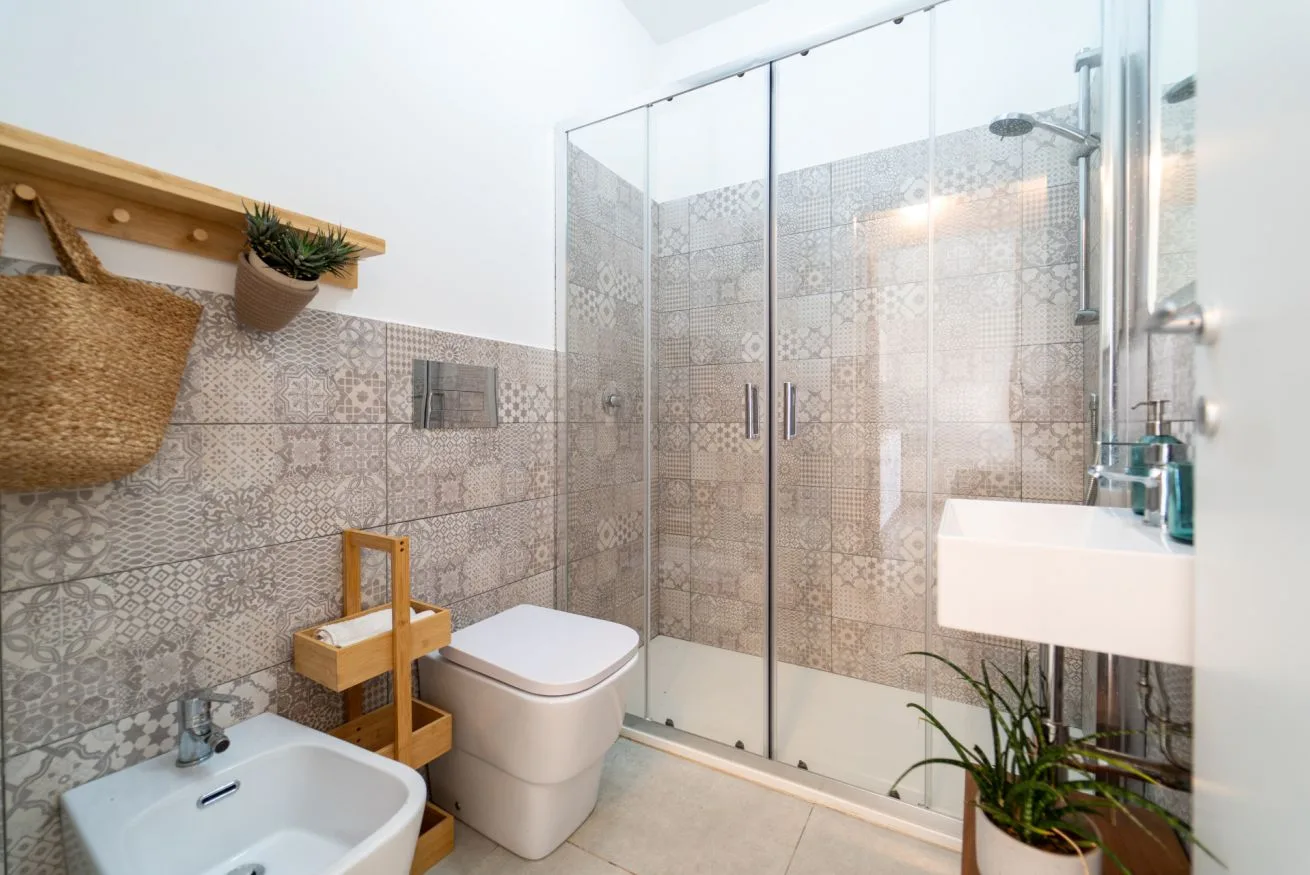 A tiled bathroom with a glass shower, toilet, and sink.
