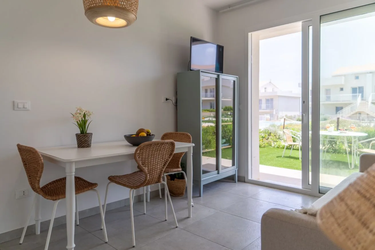 A dining area with a table and seating beside large glass doors.