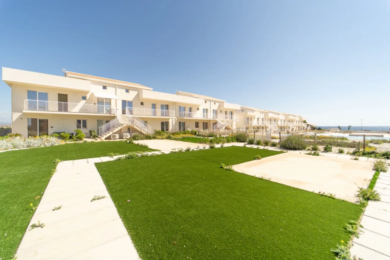 A row of modern buildings overlooks landscaped lawns and paved walkways.