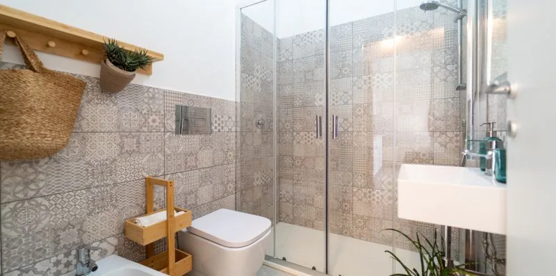 A bathroom with a glass shower, toilet, and wall-mounted sink.