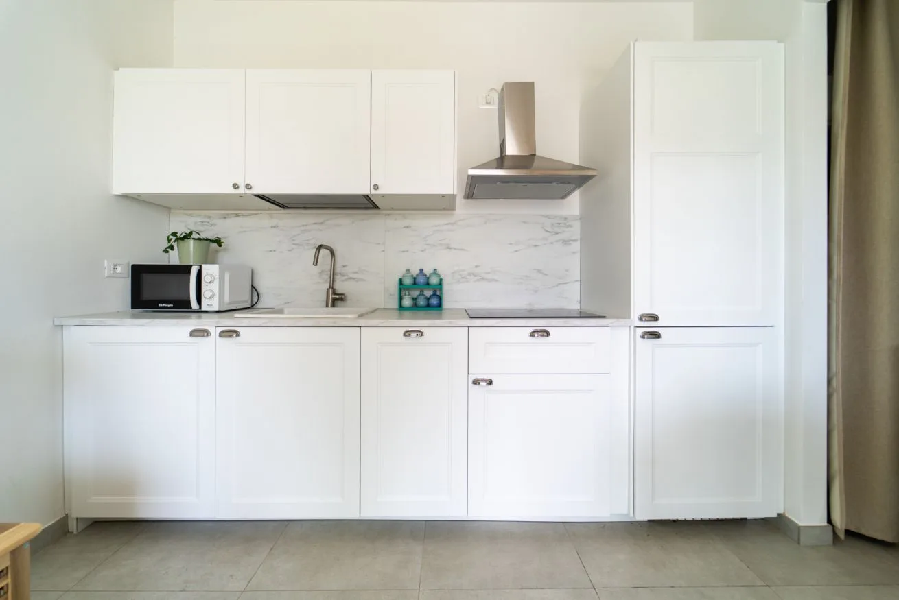 A bright white kitchen with cabinets, a sink, and a countertop.