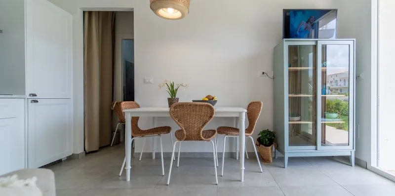 A dining area with a table and woven chairs beside a glass-front cabinet.