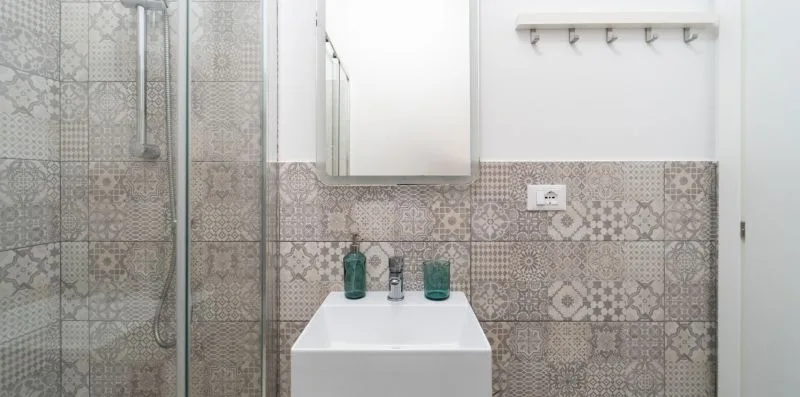 A tiled bathroom with a glass shower and a white sink cabinet.