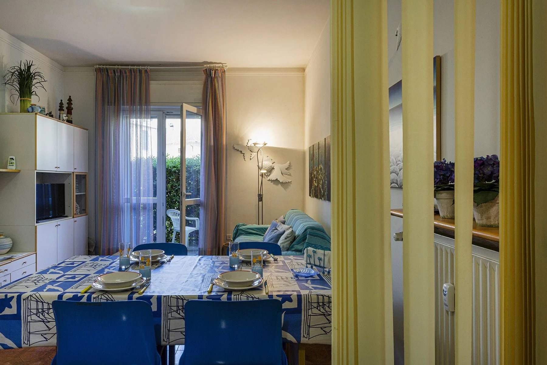 Una zona de estar y comedor con una mesa puesta y asientos junto a una ventana.