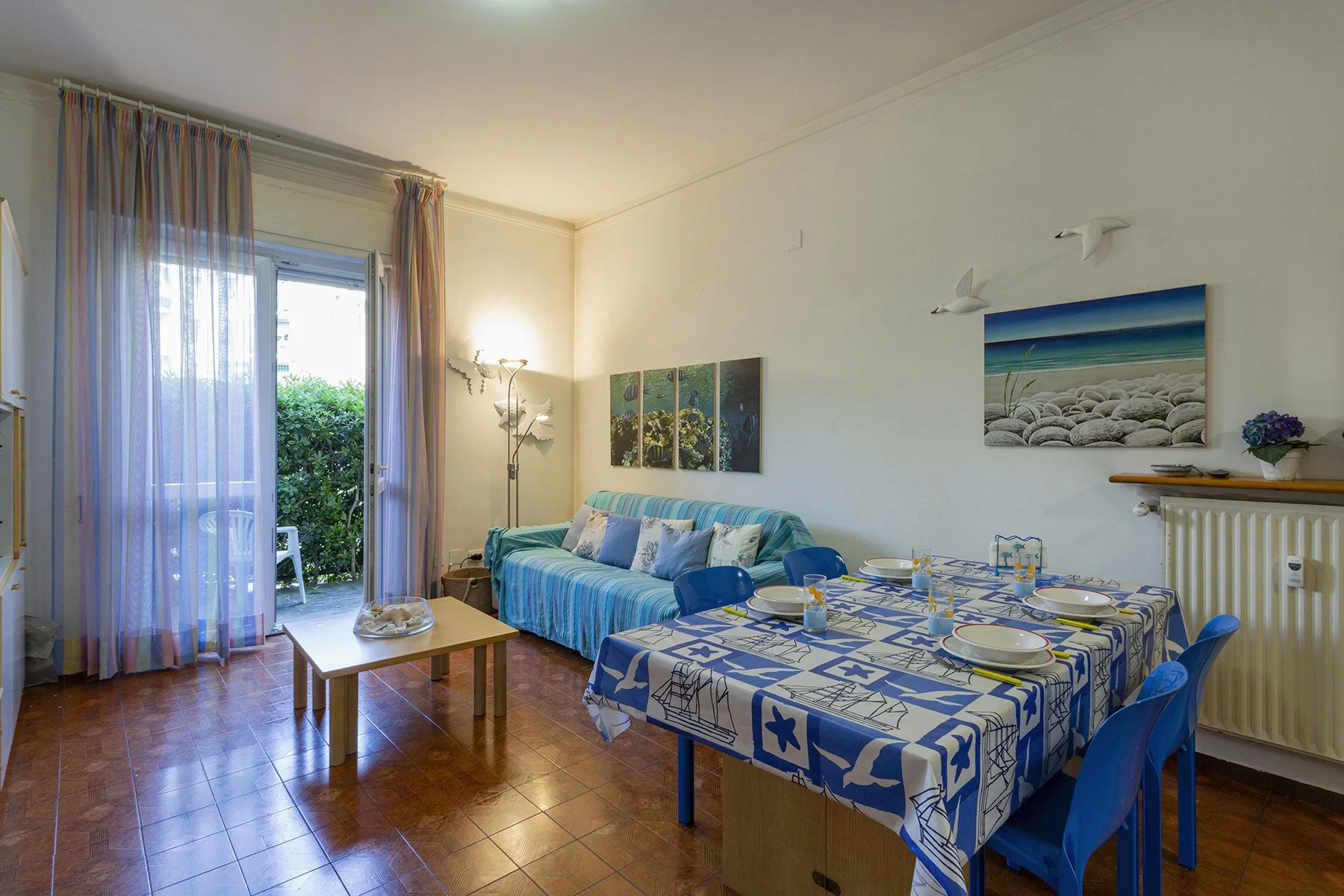 Una sala de estar y comedor con asientos azules y una mesa junto a la ventana.