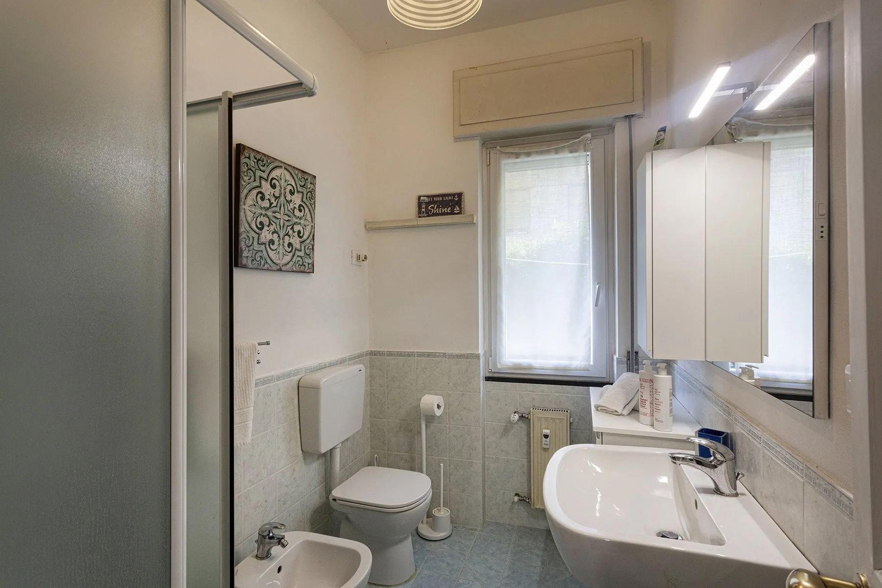 Un baño luminoso con lavabo, inodoro y ventana.