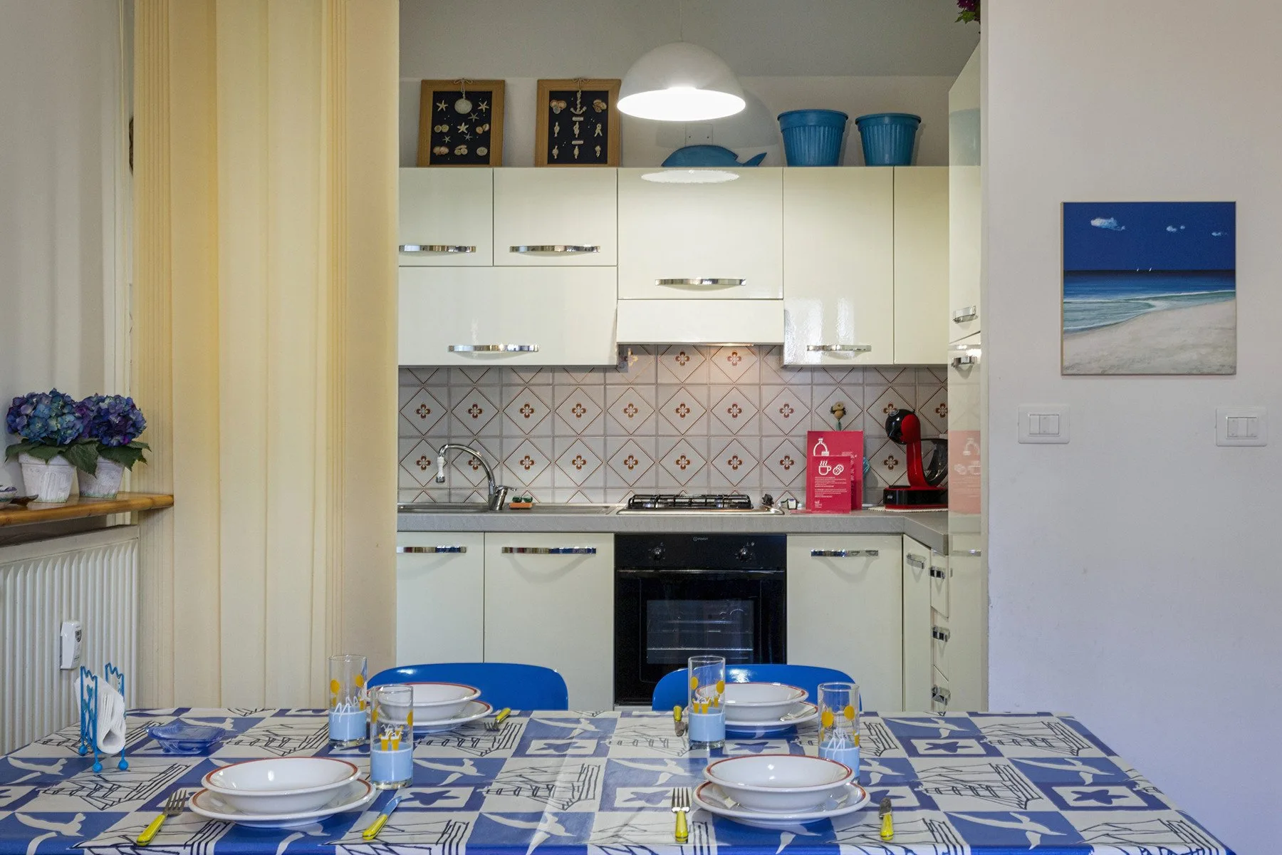 Una cocina con gabinetes blancos, una estufa y una mesa puesta con platos.