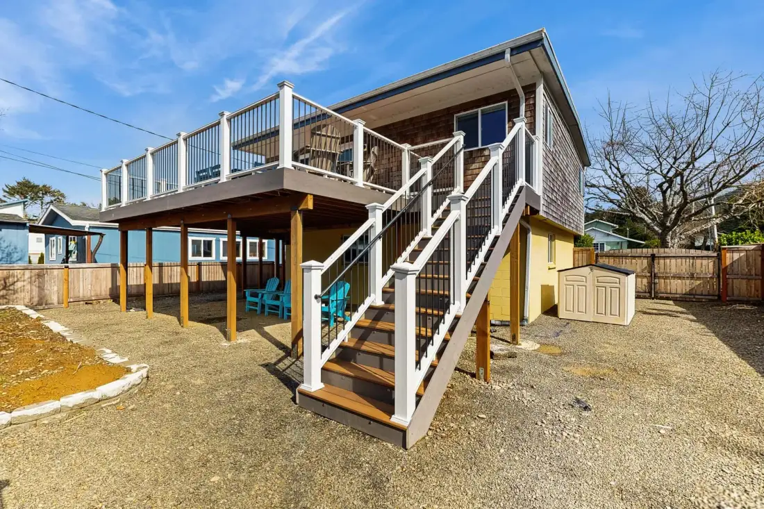 An elevated wooden deck with stairs overlooks a fenced yard.