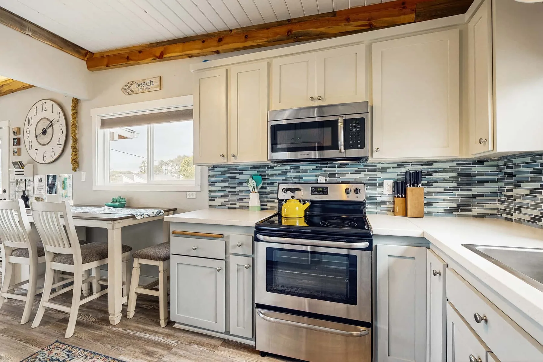 A bright kitchen with white cabinets, a tiled backsplash, and a central range.