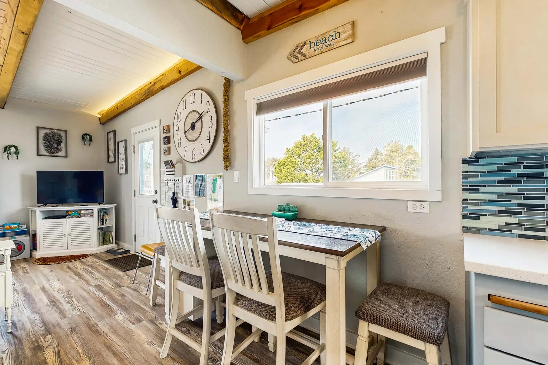 A dining area with a table and chairs beside a large window.