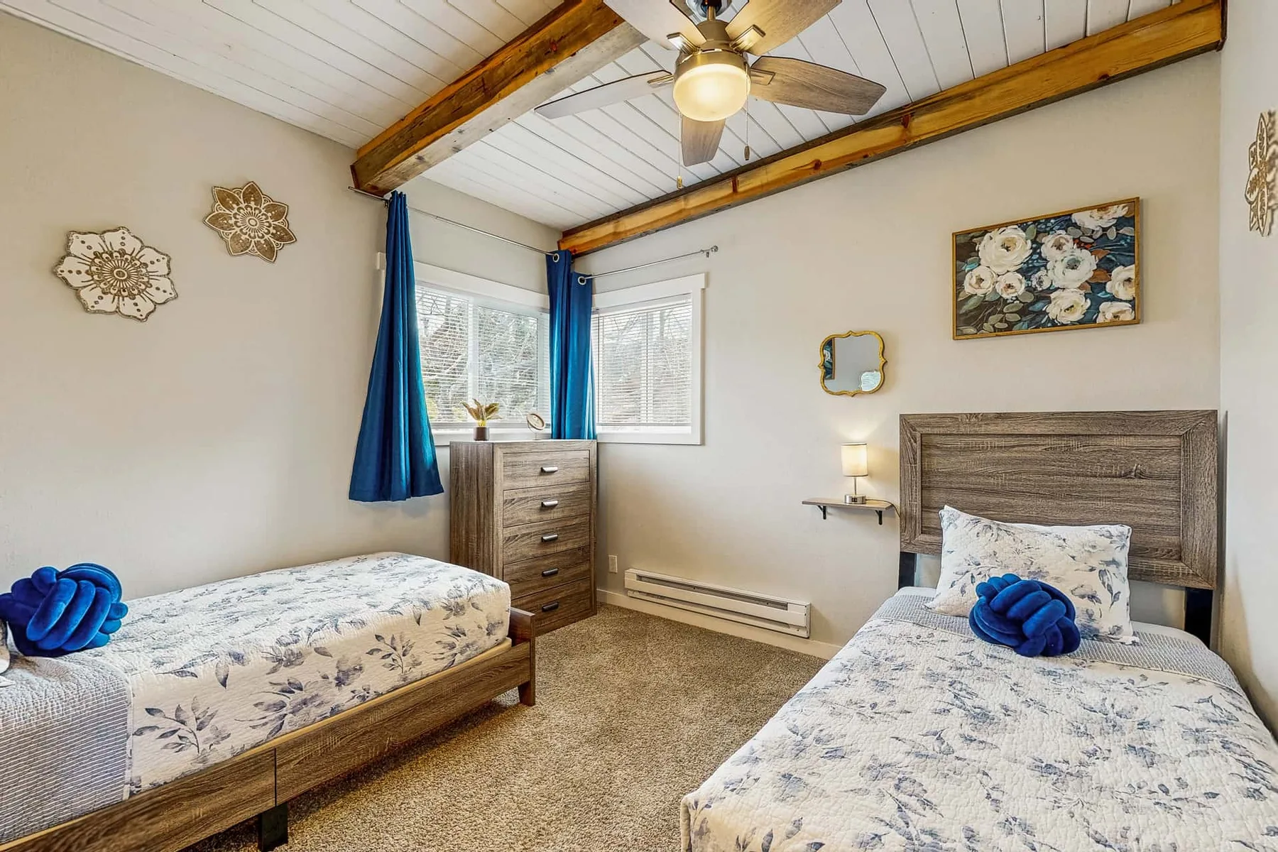 A bedroom with two beds, floral bedding, and a ceiling fan.