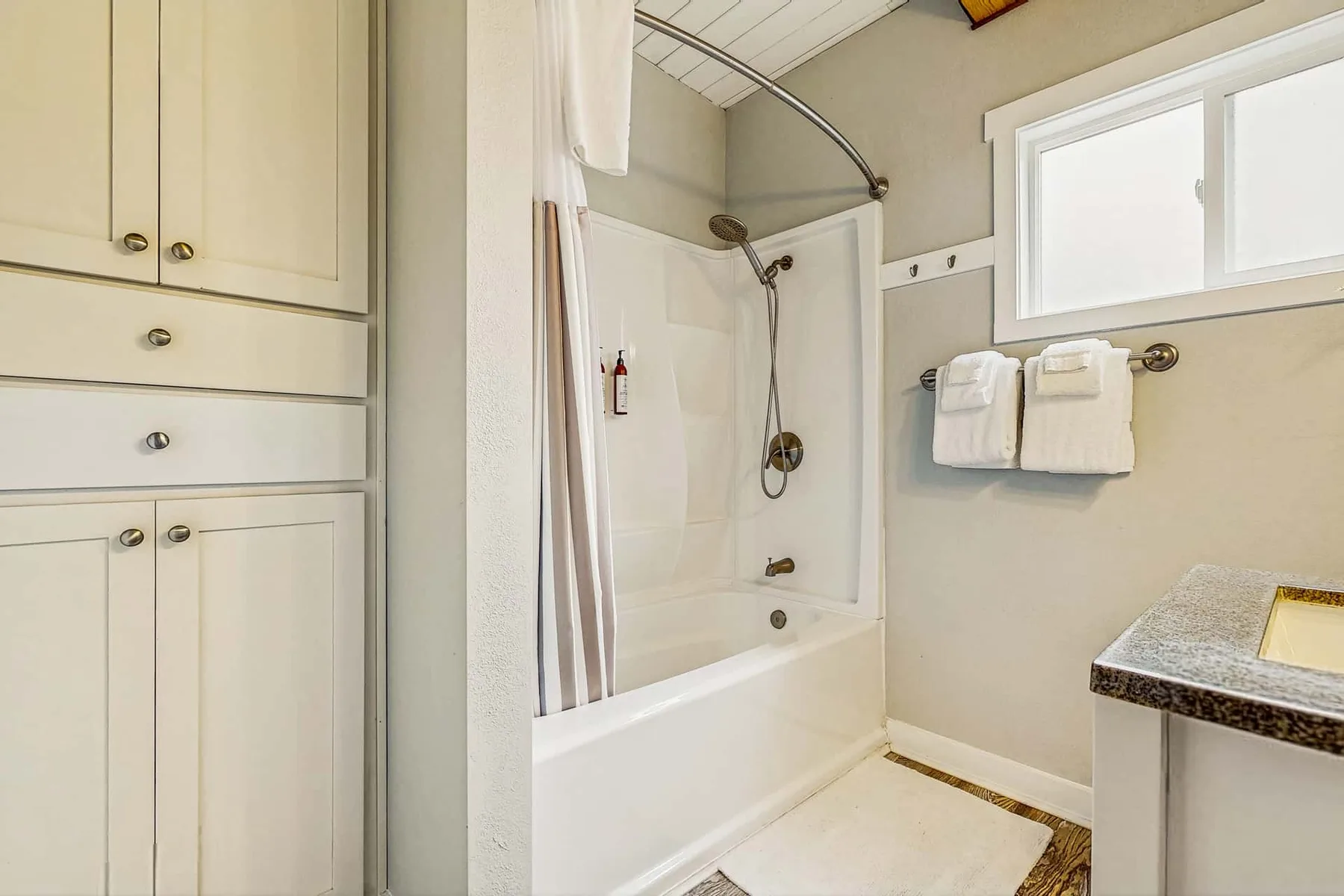 A bathroom with a bathtub and shower beside a vanity.