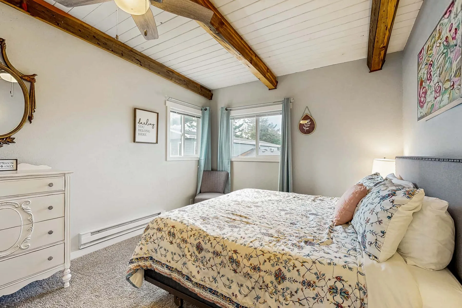 A bedroom with a bed beneath a sloped ceiling and windows.