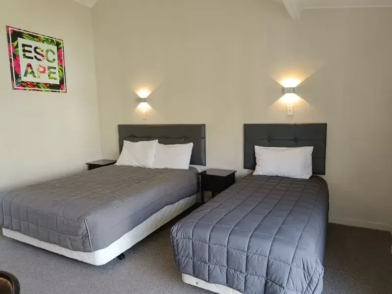 Habitación tipo estudio con dos camas individuales y una sensación de refugio en un jardín en The Furlong Motel, South Taranaki