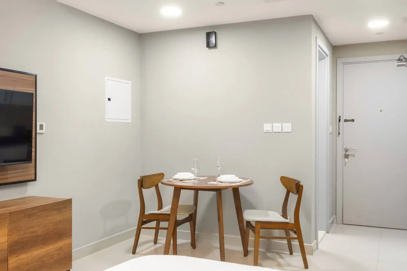 A small dining area with a round table and wooden seating beside the entry door.