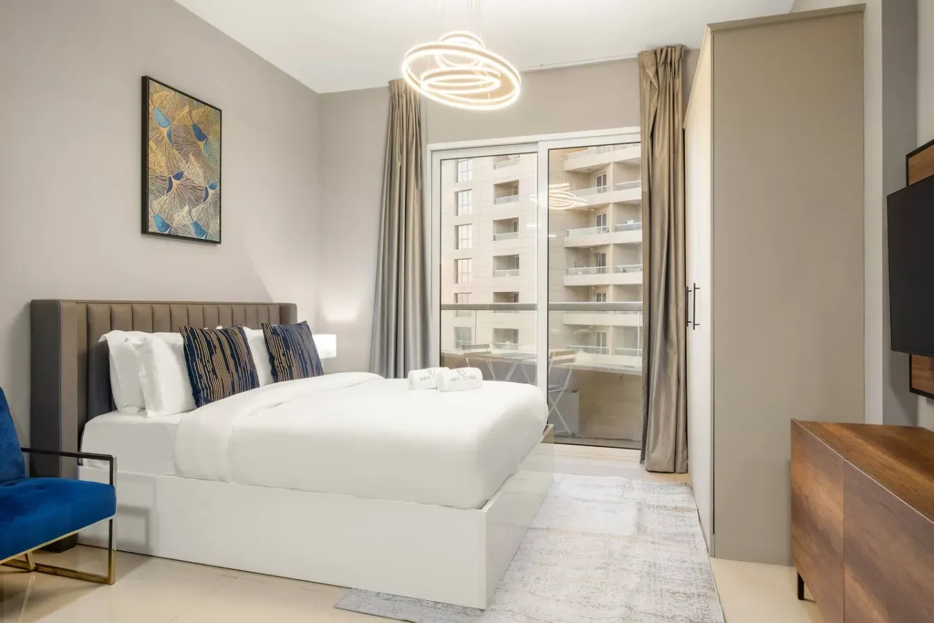 A bright bedroom with a neatly made bed beside a large window.