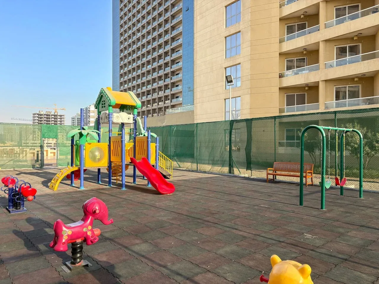 A children's playground with colorful play equipment and a rubber-paved surface.