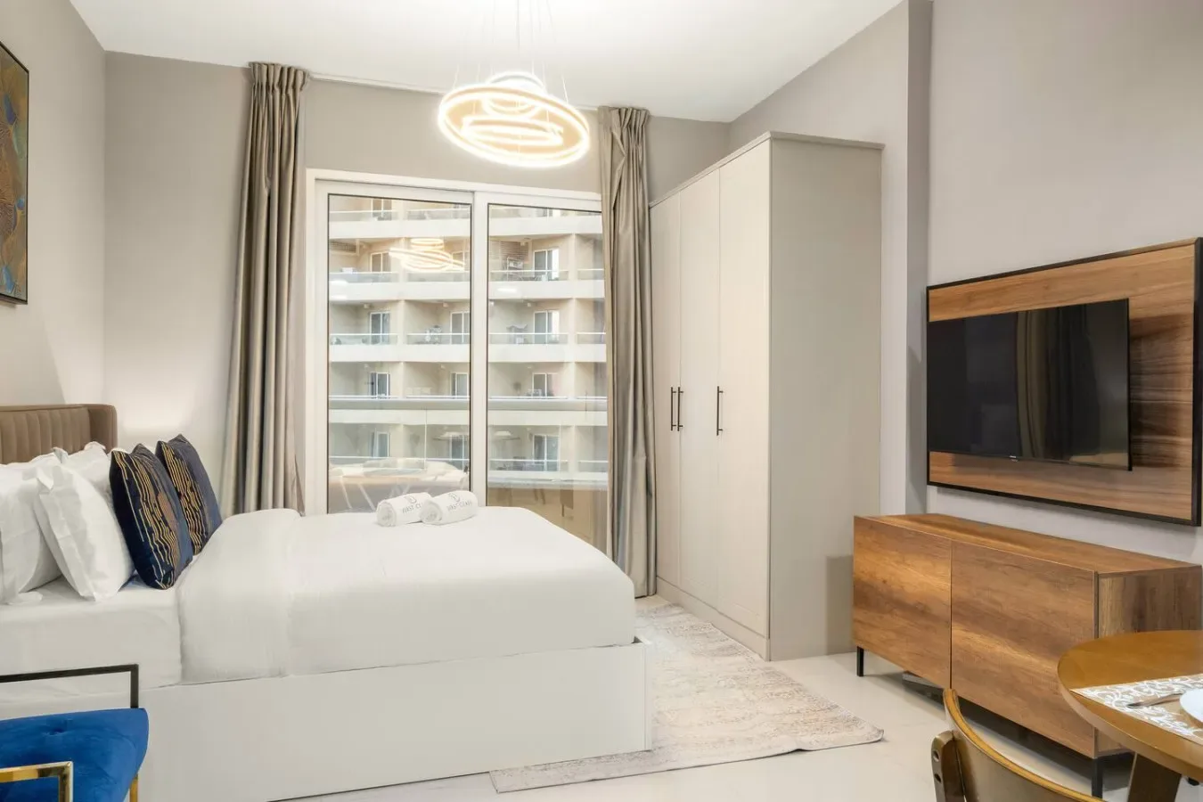 A bright bedroom with a bed, wardrobe, and television.