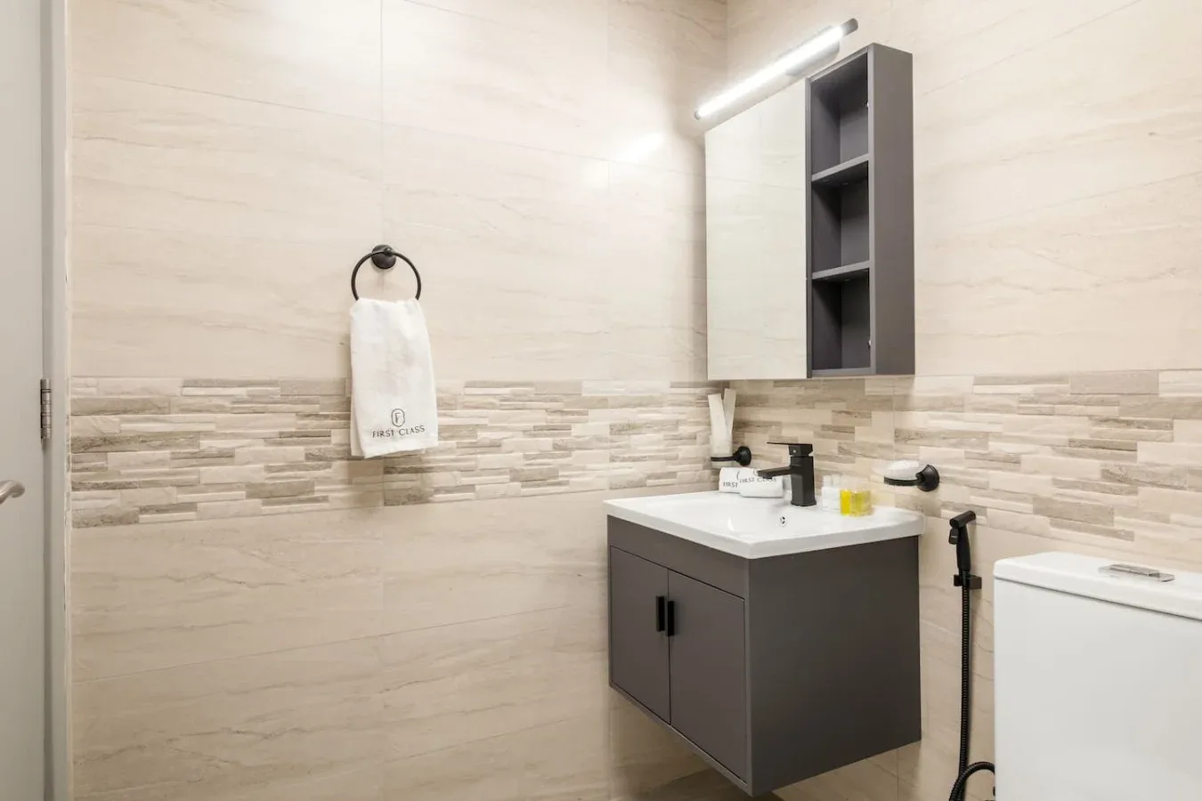 A bathroom with a sink, mirror, and tiled walls.