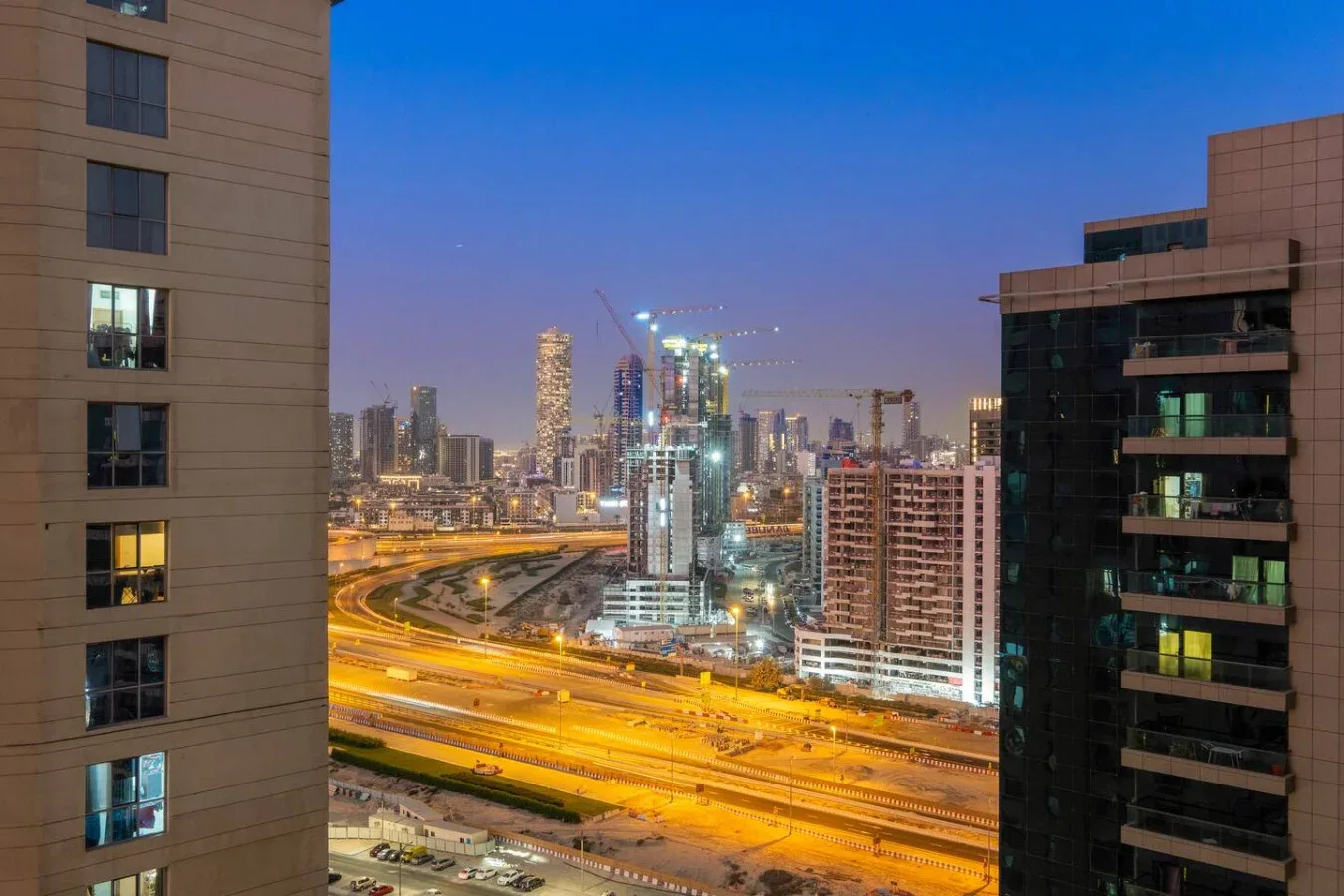 A city skyline at dusk overlooks illuminated highways and surrounding buildings.