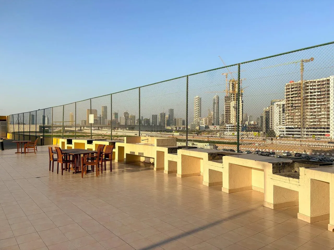 A rooftop terrace with outdoor tables overlooks a city skyline.