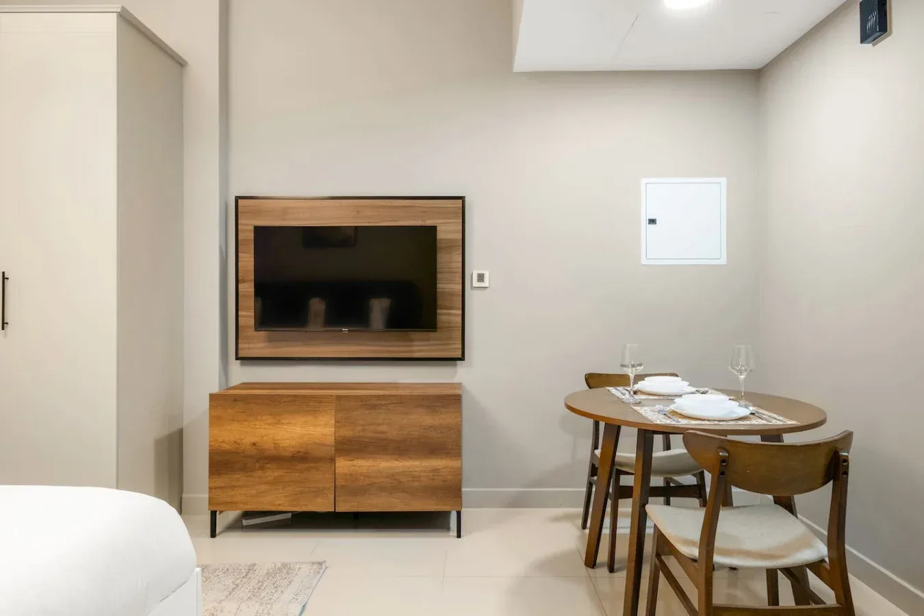 A dining area with a wooden table and chairs beside a wall-mounted television.