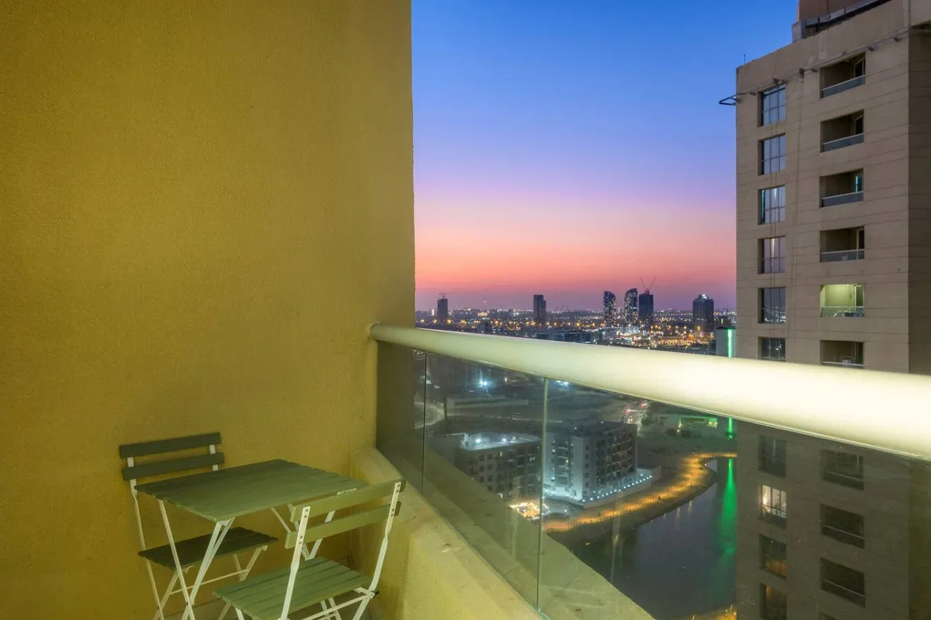 A balcony overlooks city buildings and a waterway at dusk.