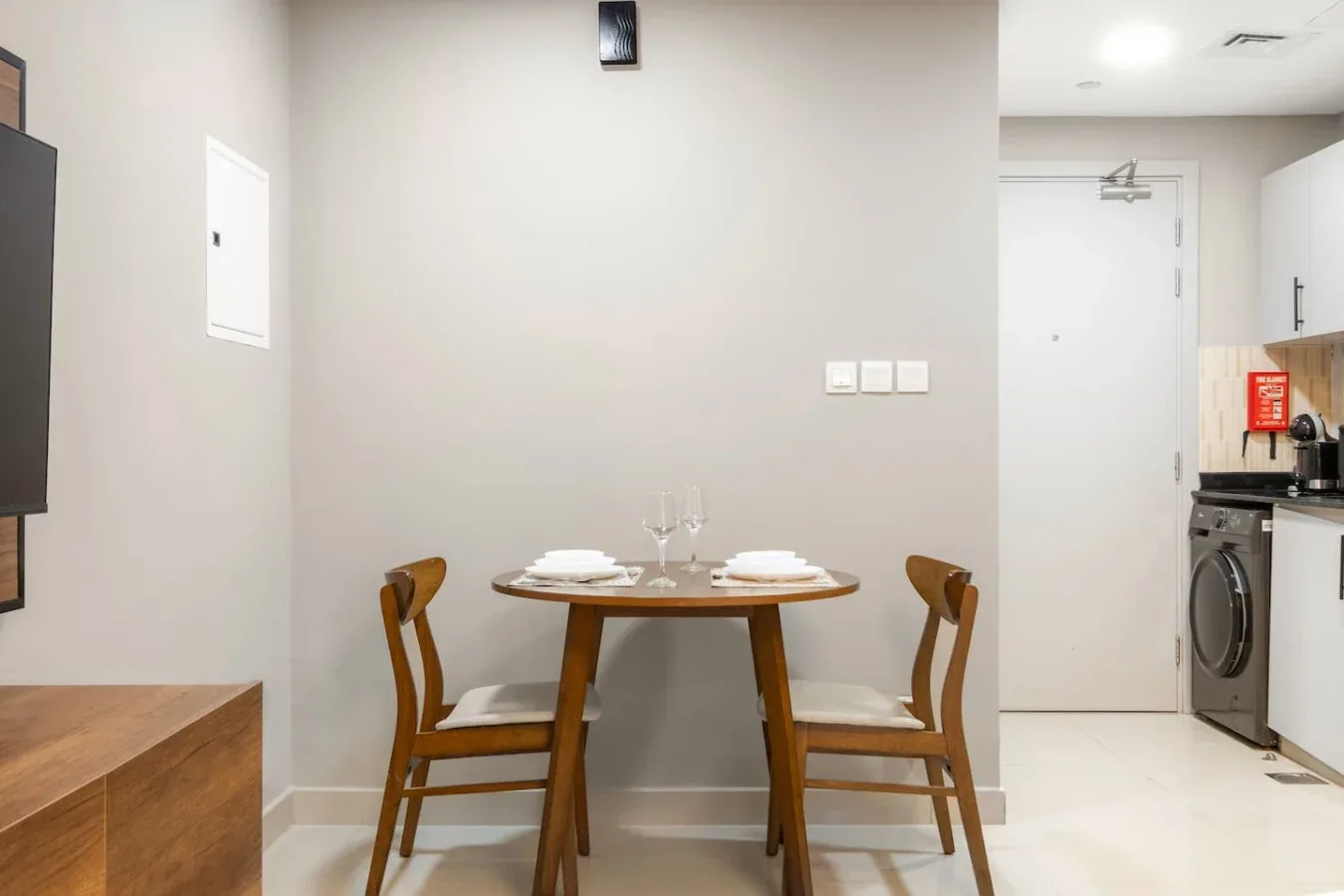 A small dining area with a round table and wooden seating beside a kitchenette.