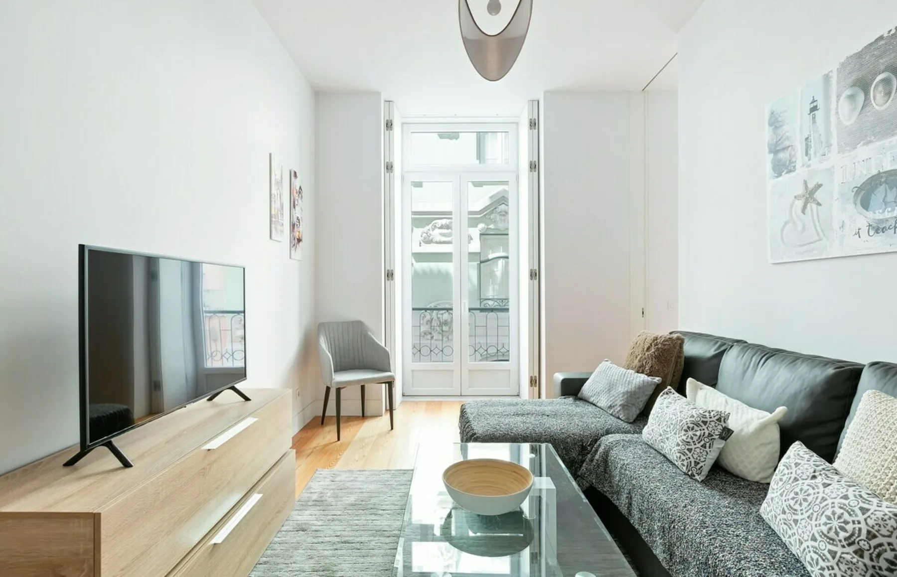 Living room with seating, a television, and glass doors opening to a balcony.