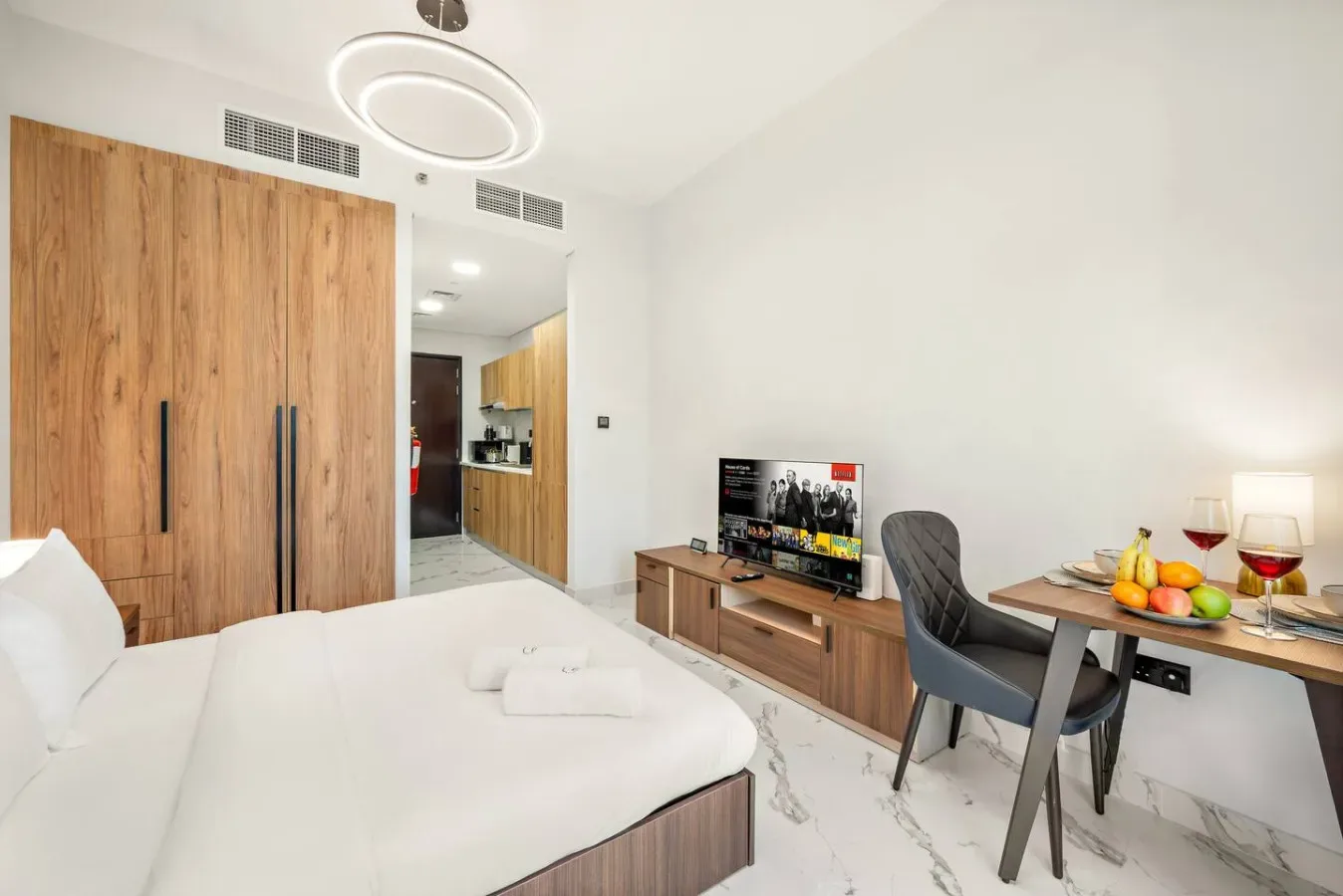 Un dormitorio luminoso con una cama, muebles de madera y un televisor.