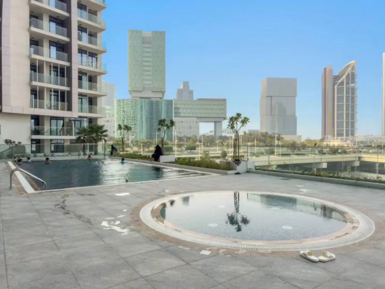 A rooftop pool deck with a large swimming pool and a round shallow pool.
