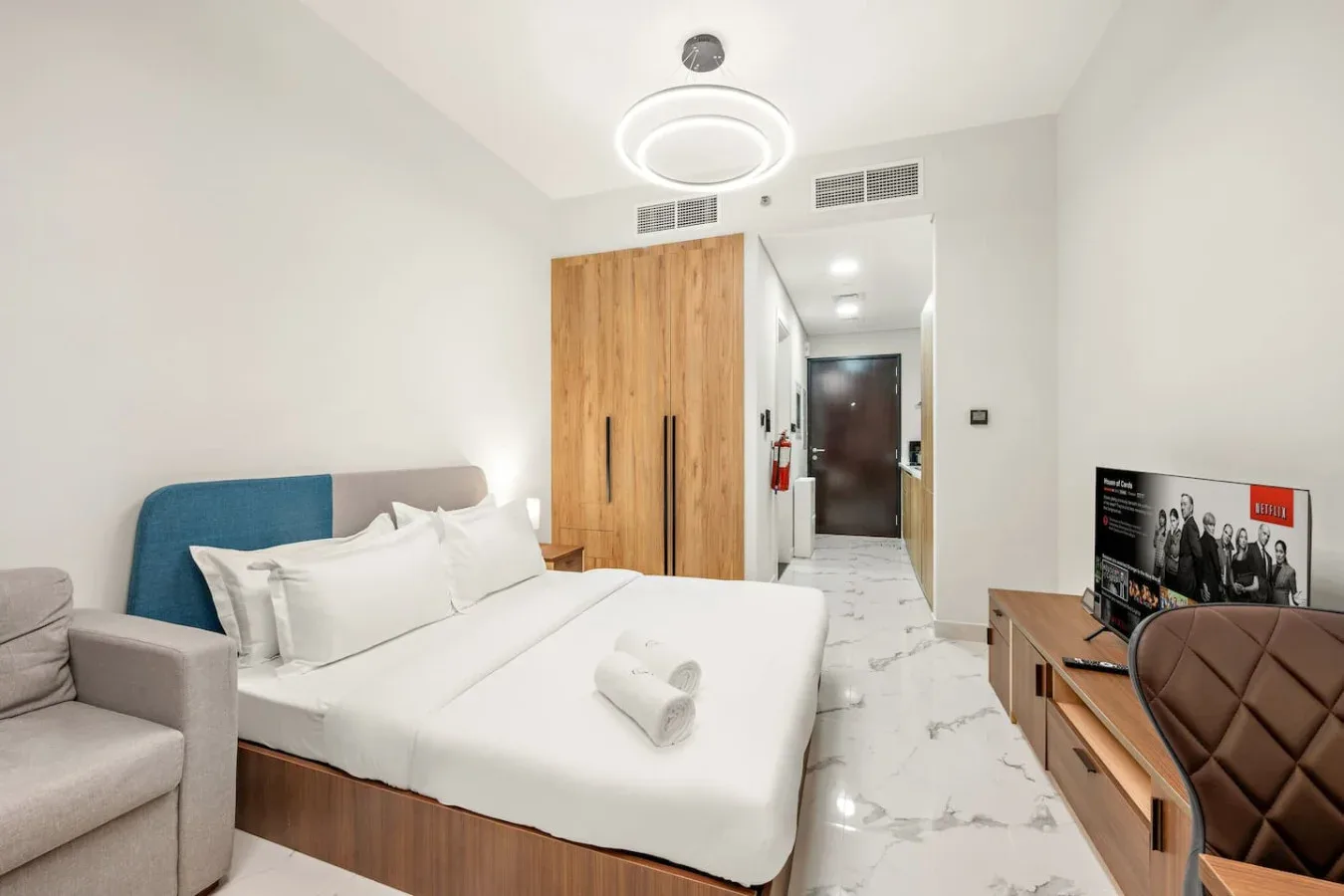 Un dormitorio luminoso con una cama grande, un armario y un televisor.