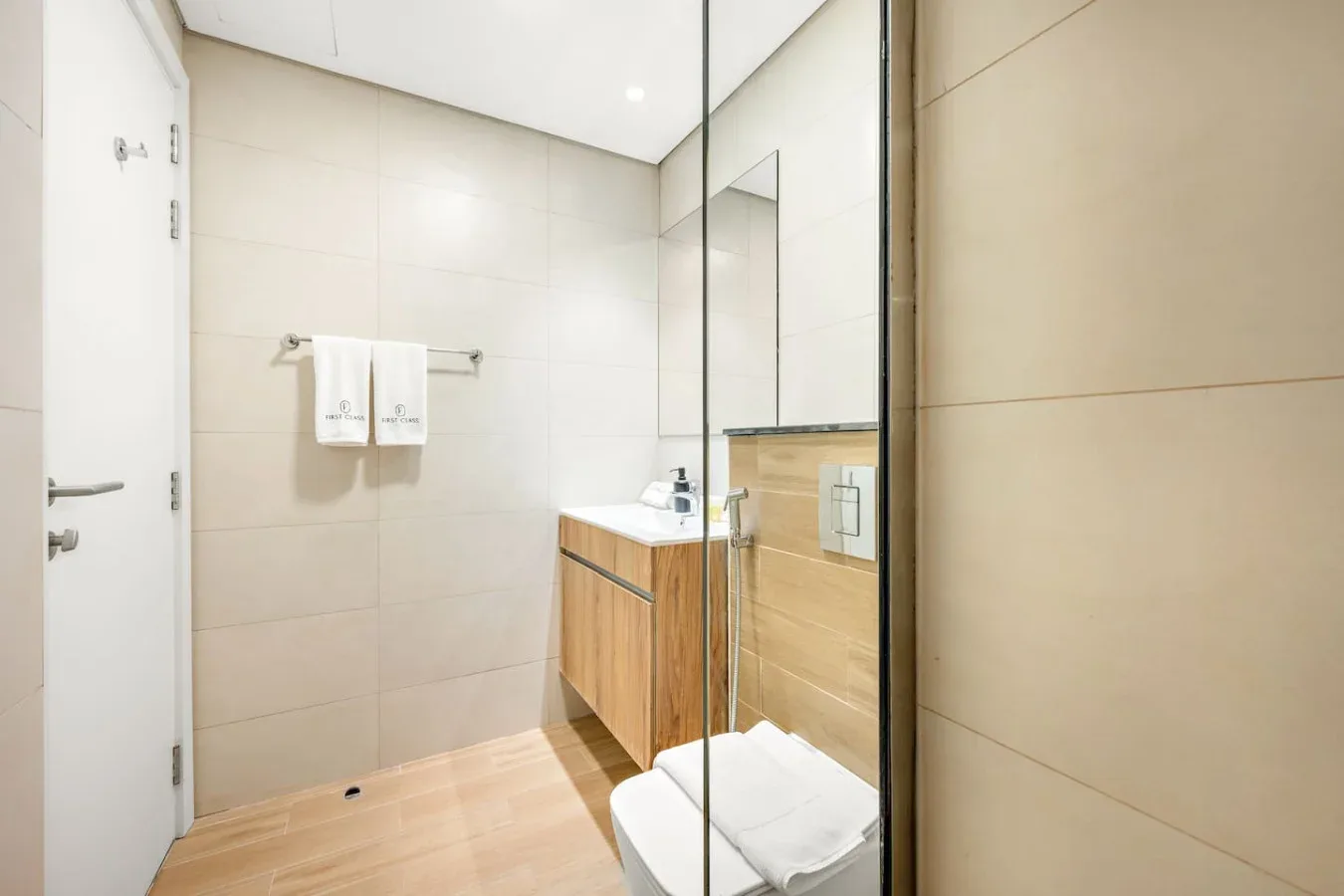 Un baño luminoso con un mueble de madera y una mampara de vidrio.