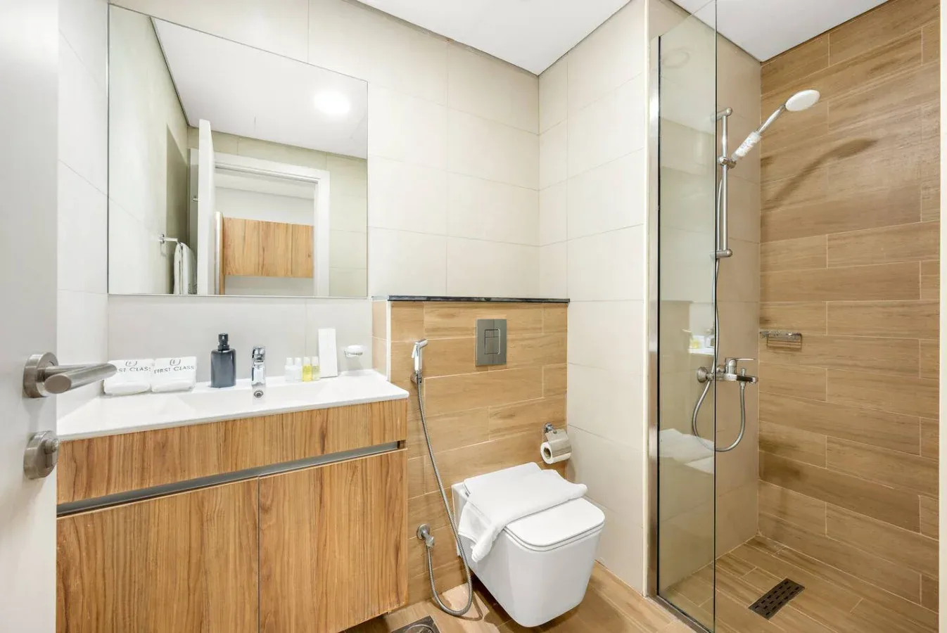 Un baño moderno con lavabo de frente de madera, inodoro y ducha de vidrio.
