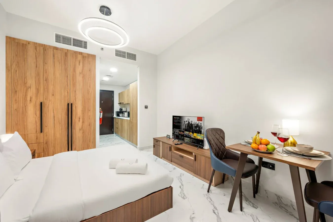 Un dormitorio con cama, armario de madera y mesa de comedor.