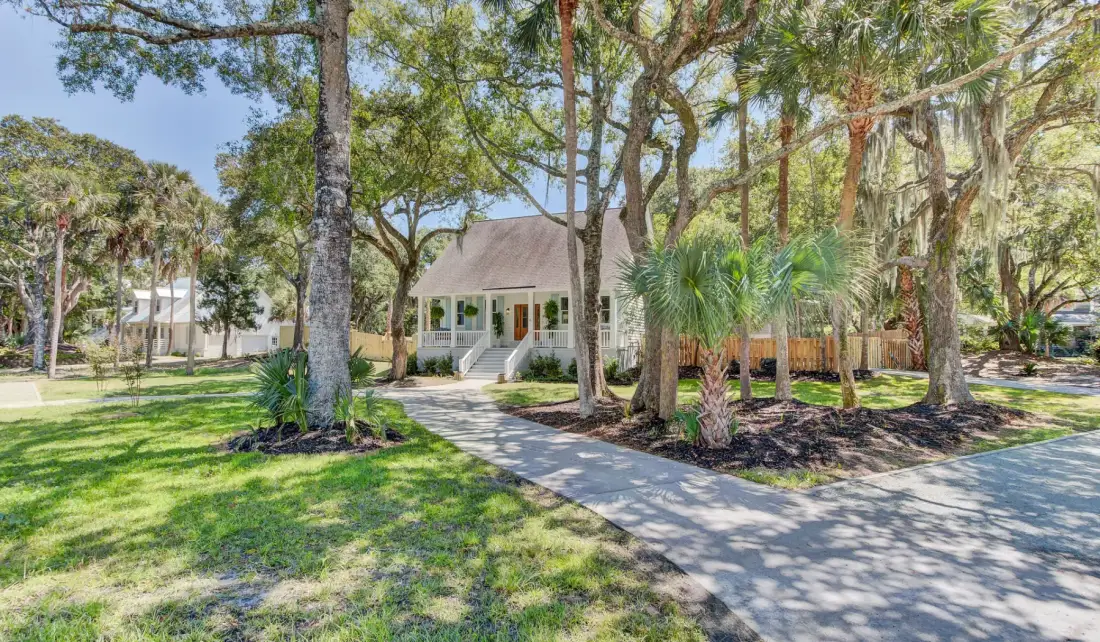 A house sits among trees beside a curving paved walkway.