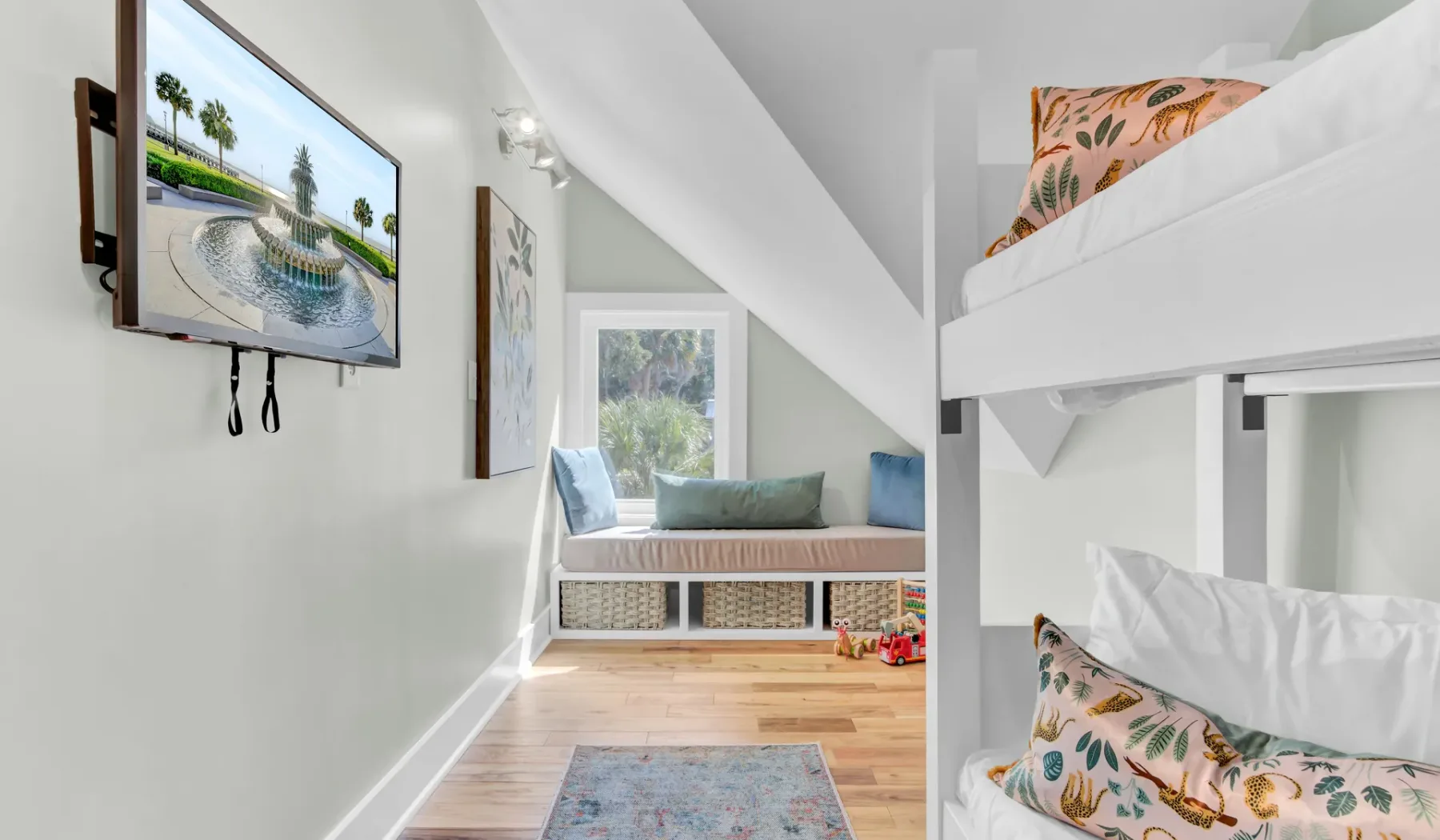 A bright bedroom with bunk beds, a window, and a wall-mounted television.