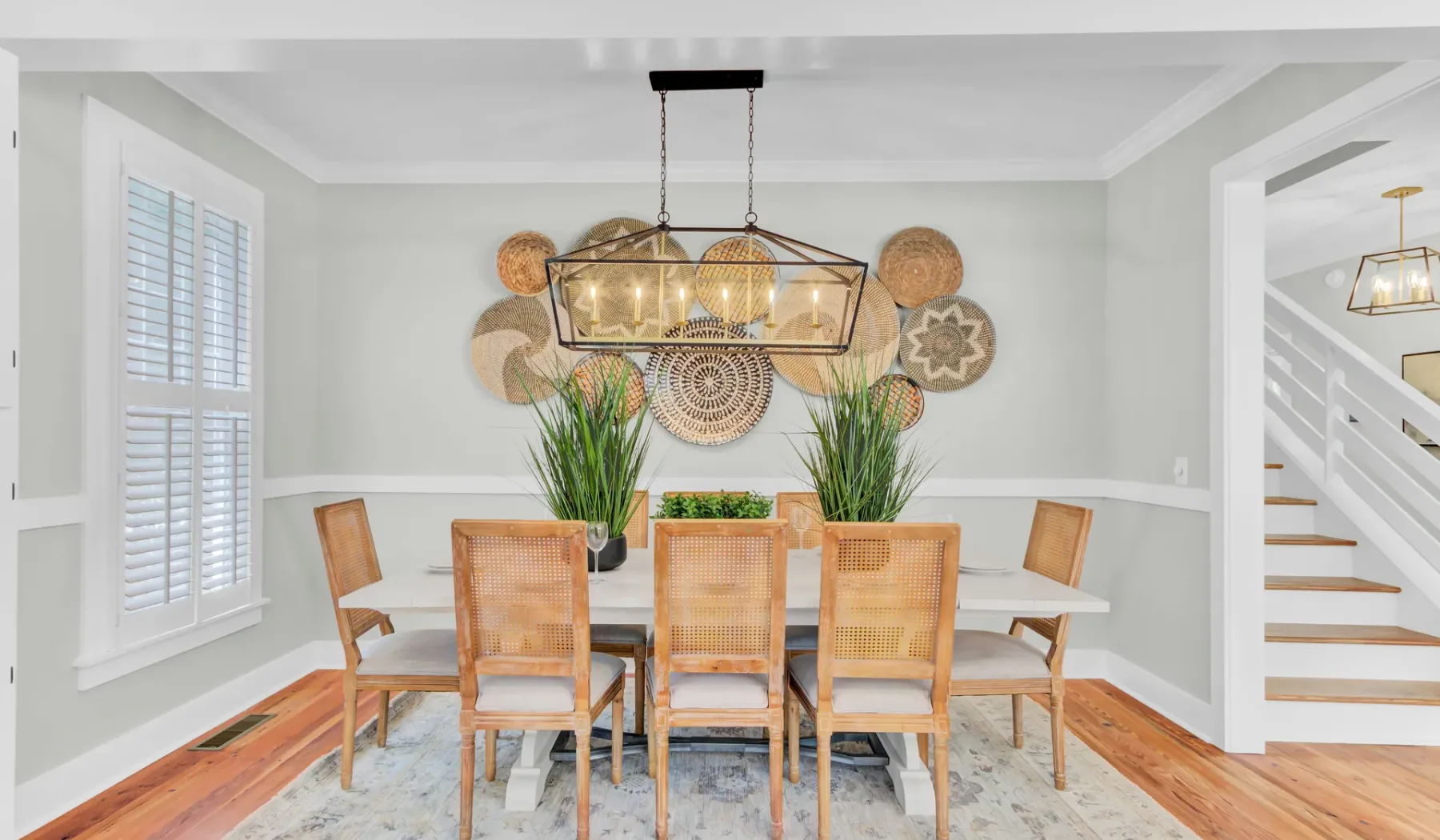 A dining area with a wooden table, woven chairs, and a hanging light.