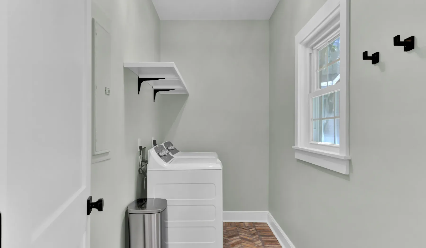 A laundry room with a washer, dryer, and wall shelves.