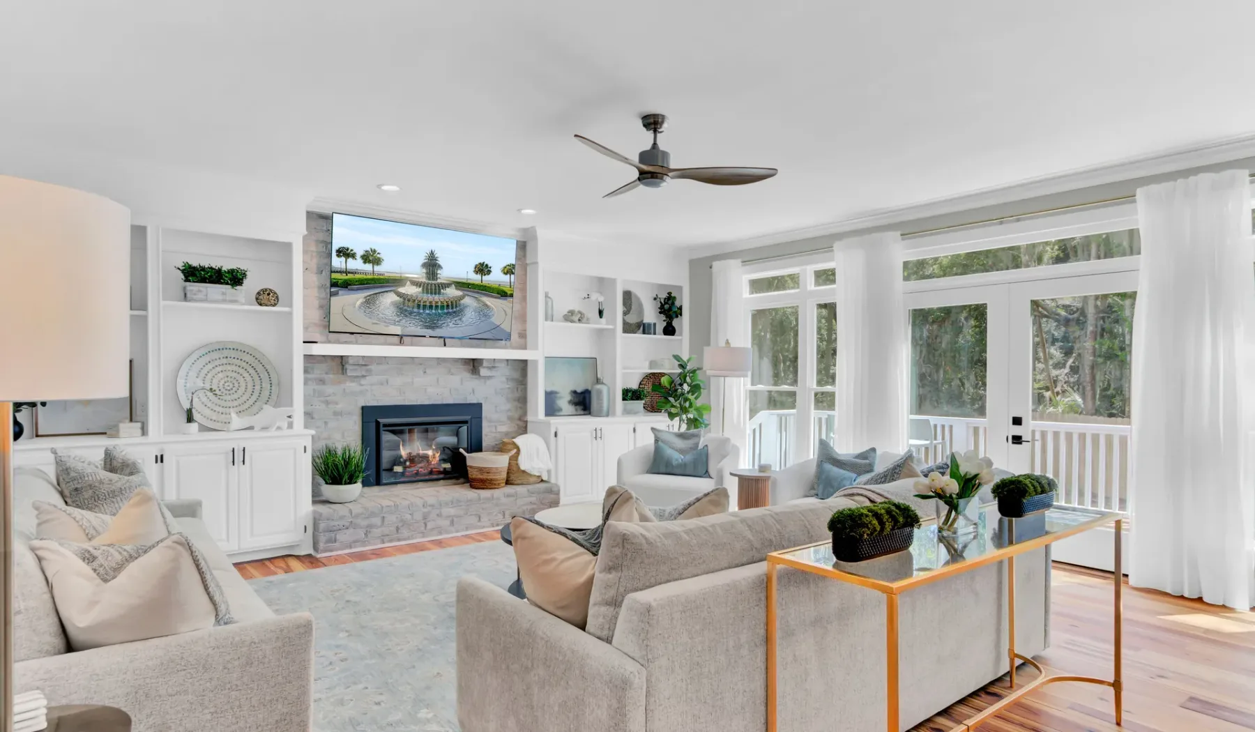 A bright living room with seating, a fireplace, and large windows.
