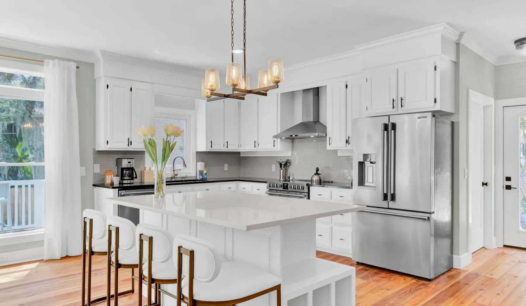 A bright kitchen with white cabinetry, stainless steel appliances, and a central island.