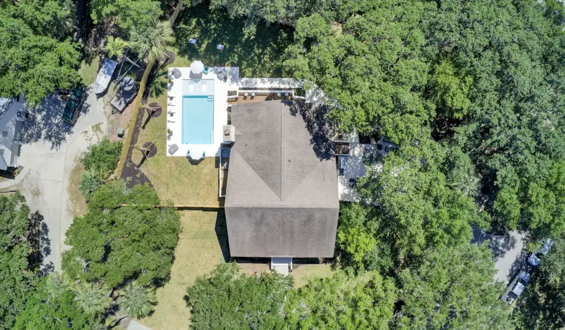An aerial view shows a building and swimming pool surrounded by trees.