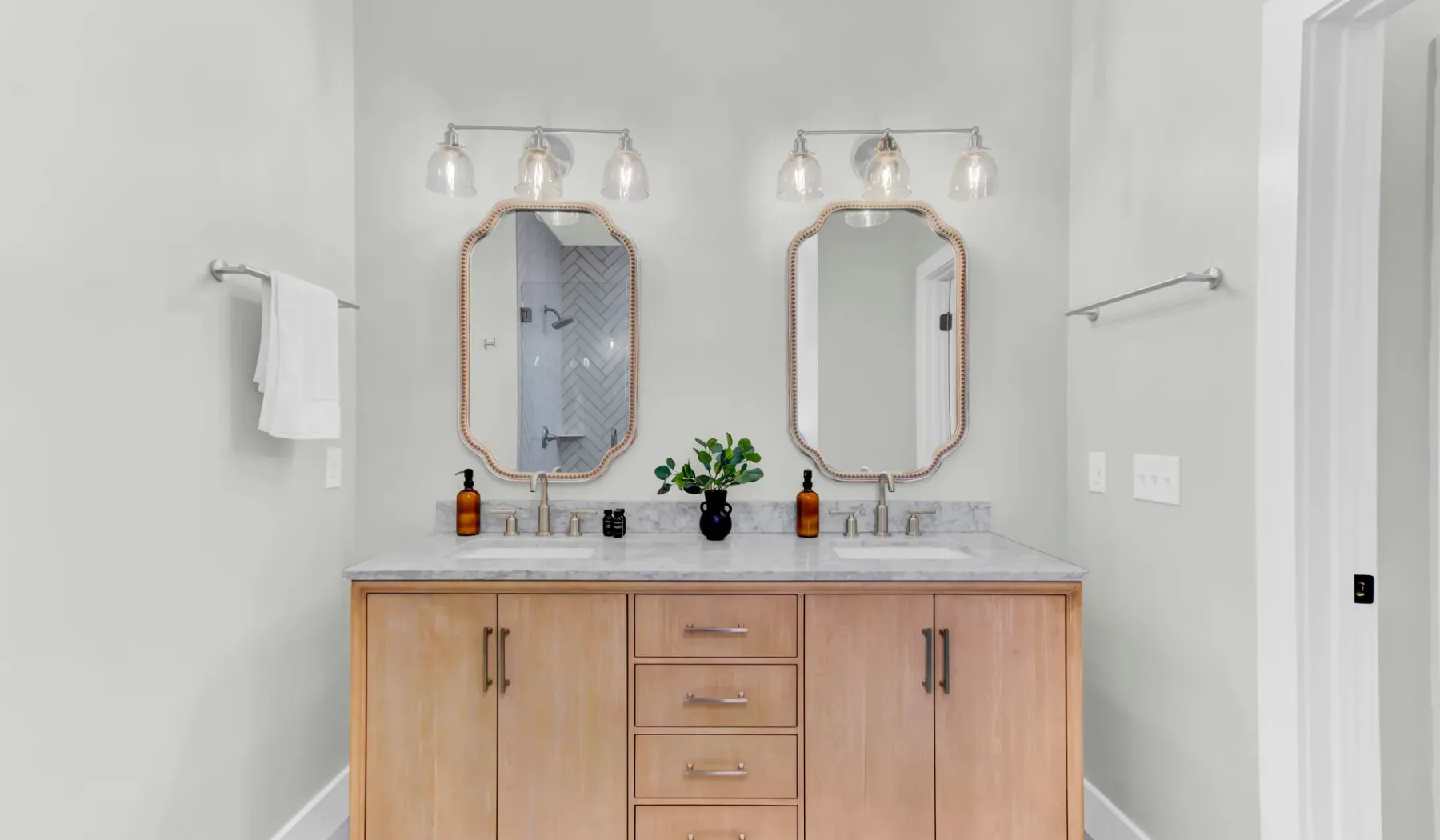 A bathroom vanity with two sinks, mirrors, and wooden cabinetry.
