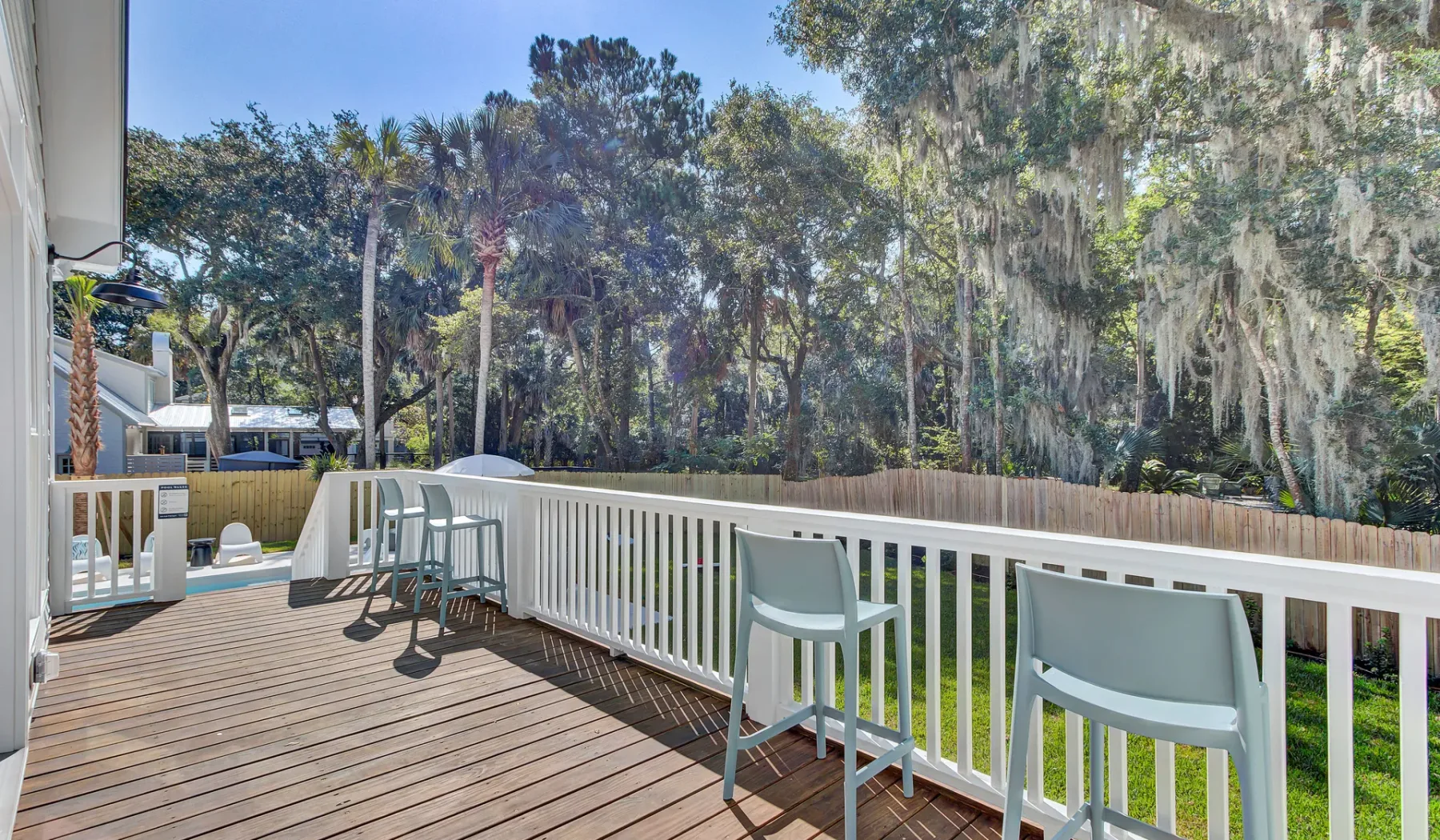 A wooden deck with white railings and seating overlooks a tree-lined landscape.