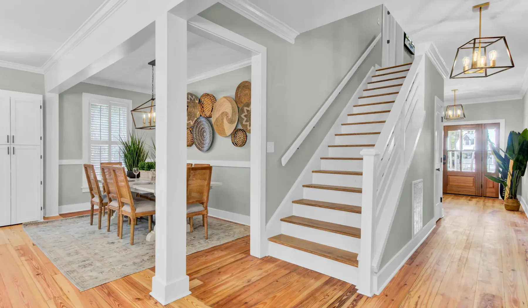 A bright home entryway with a staircase beside a dining area.