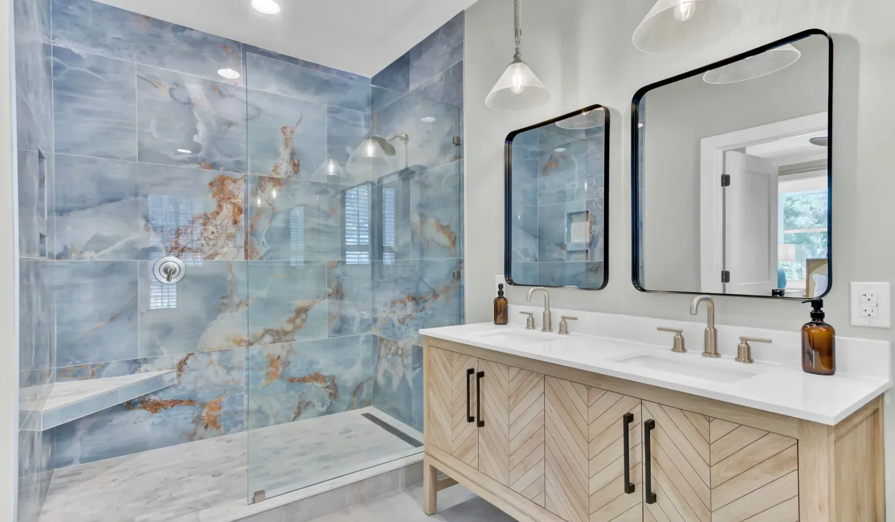 A tiled bathroom with a glass shower and a long vanity.