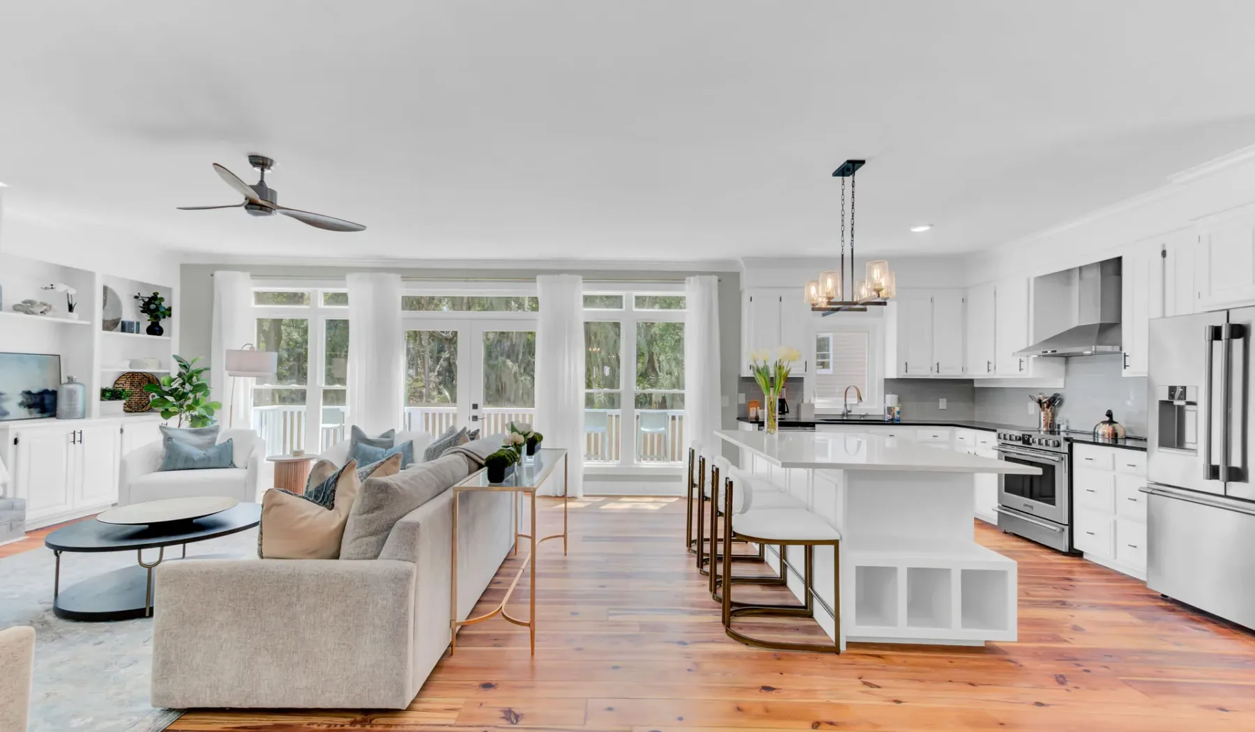 A bright open-plan living room and kitchen with large windows and a central island.