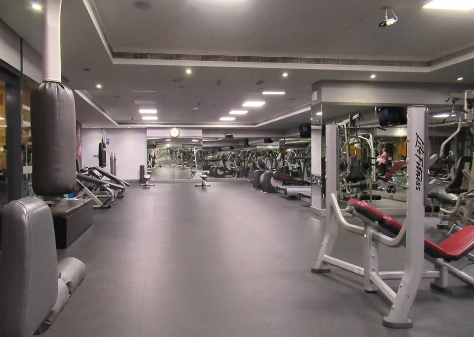 Un gimnasio con máquinas de ejercicio y bancos de pesas a los lados.