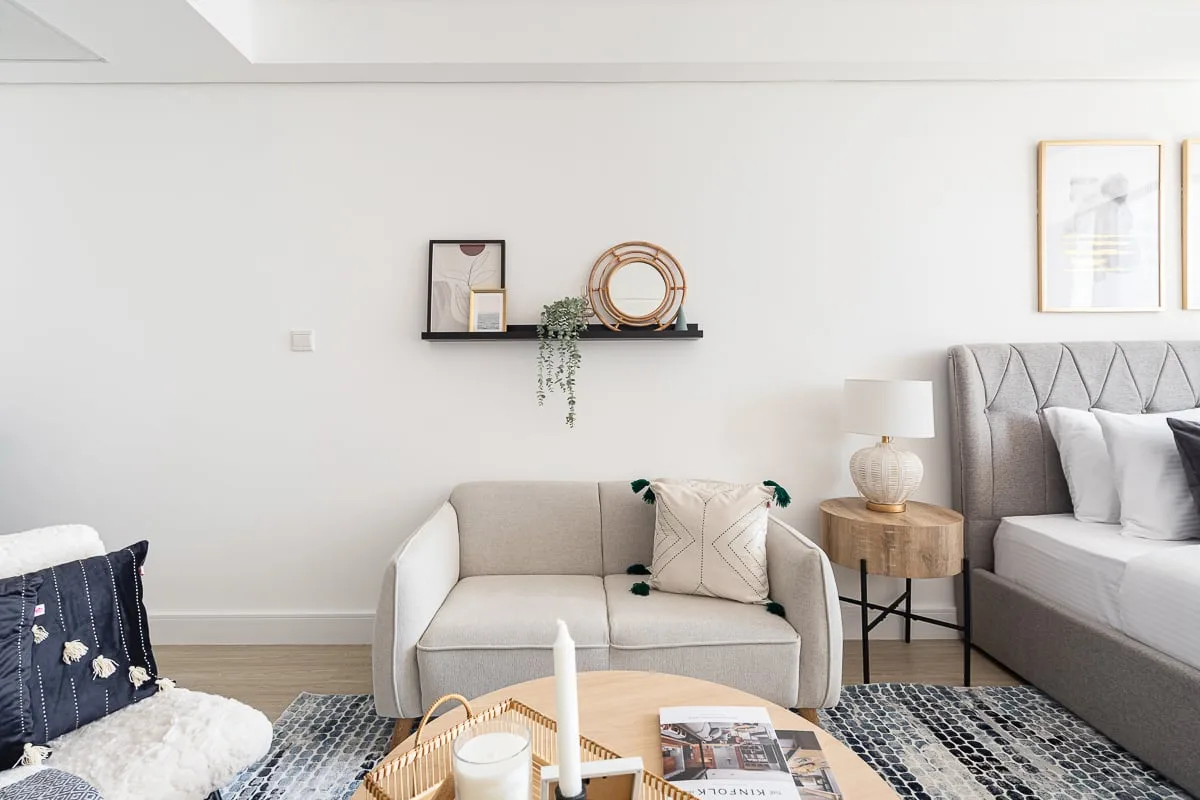 Un dormitorio luminoso con una cama, un sofá pequeño y una mesa de centro.